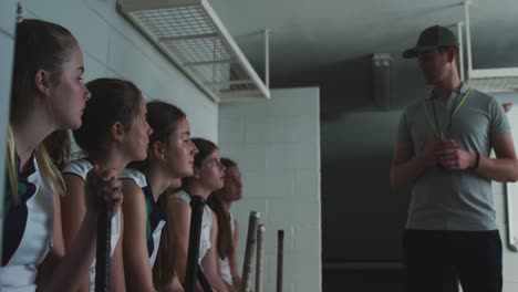 Hockey-coach-talking-with-female-players-in-locker-room