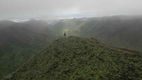 flyover: man on high moanalua mountain ridge overlooks honolulu below