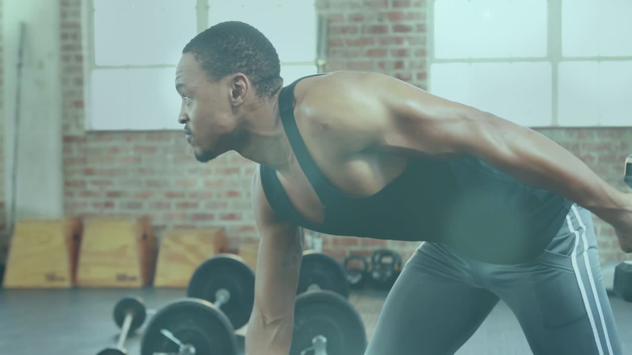 Male trainee performing one-arm rows starting bent over bracing hand, pulling dumbbell for strength