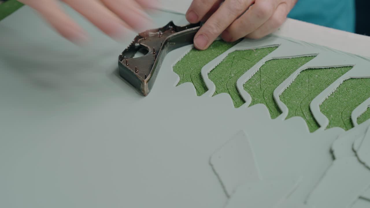 primo piano di artigiano che taglia parti di scarpe in pelle con una pressa di metallo