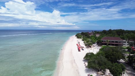 drone zooming out along sandy shoreline with turquoise waters and tropical vegetation