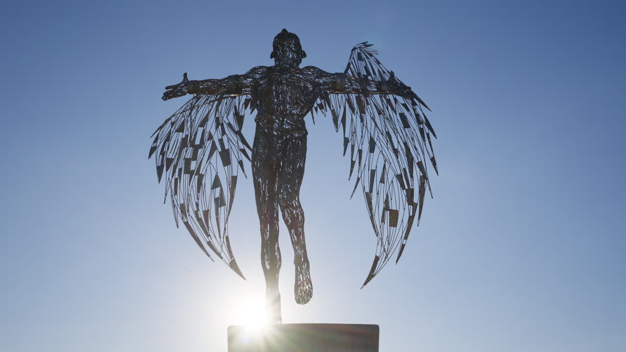 Ayia Napa, Cipro - 26 febbraio 2026: Drammatica silhouette della scultura di Icaro con le ali spiegate sul lungomare di Ayia Napa.