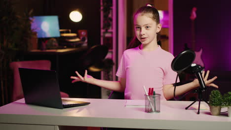 cheerful gen z kid shooting video for online platforms in pink lit living room talking about her day