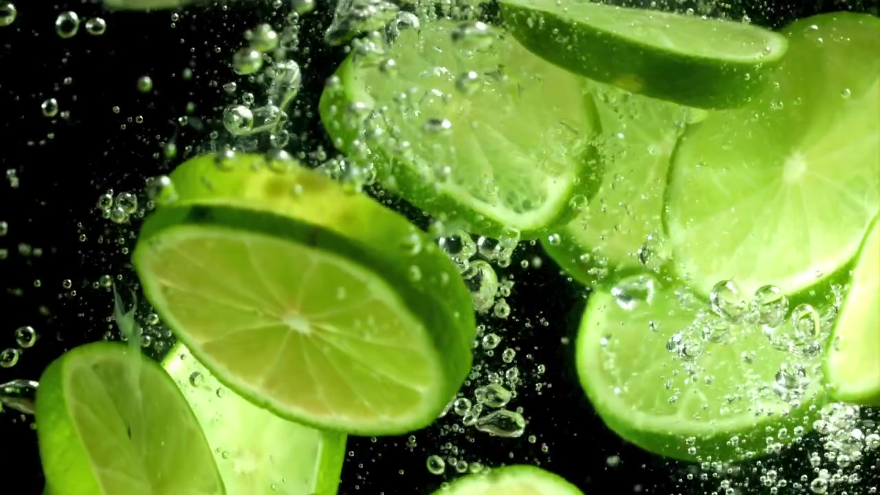 Fresh Lime Slices Splashing into Water with Bubbles