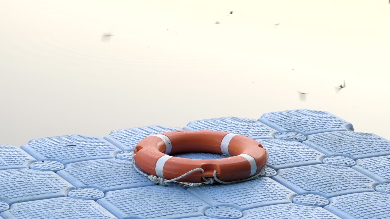 Life buoy on surface of blue plastic pontoon walkway for rescue in case of emergency