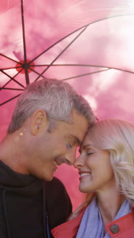 couple touching noses outdoors with umbrella