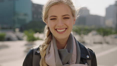 slow motion portrait of cute young blonde woman smiling happy cheerful in windy city enjoying urban lifestyle wearing scarf