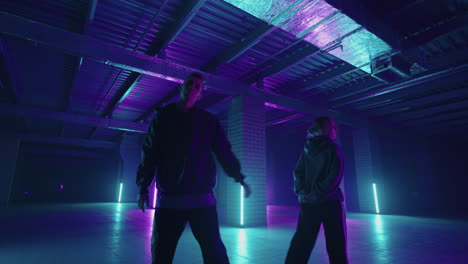 a duet of two professional dancers a man and a woman. a stylish couple dances hip-hop freestyle together in synchronously in lard lit in blue purple hues with neon light