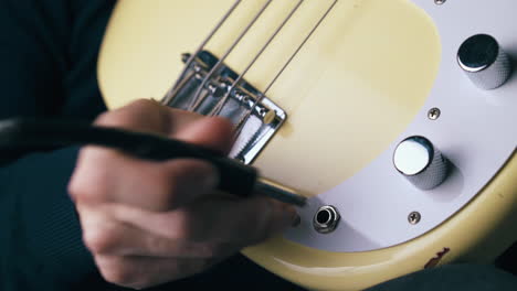 musician connects quarter-inch jack with bass guitar