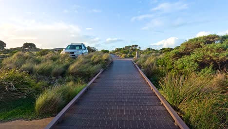 wooden walkway leading to coastal viewpoint with parked vehicles nearby