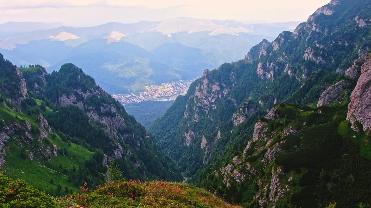 Cinematic shot of the fir, Bucegi mountains, Busteni city and skyline in Romania
