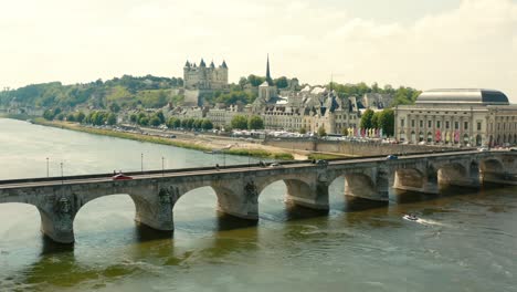 photo aérienne traversant une rivière avec un vieux pont et un beau château en arrière-plan en france