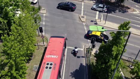 a red bus waits in santiago de chile streets traffic lights, aerial drone, taxi and cars drive along las condes neighborhood