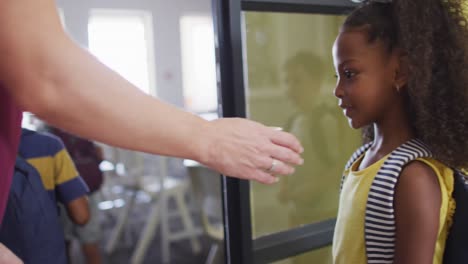 video of happy diverse pupils clapping hands with caucasian female teacher and entering classroom