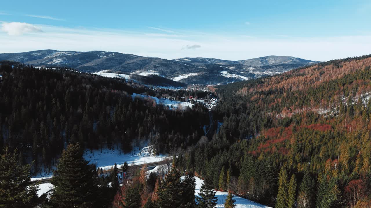 Drohnen-Luftaufnahme über einem verschneiten Bergdorf an einem sonnigen Wintertag
