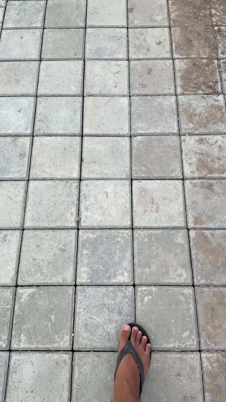 Person Walking on Concrete Paving Stones in Sandals