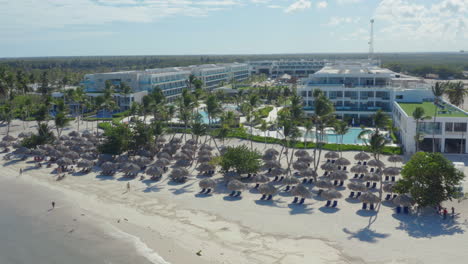 palmeras y sombrillas de paja en la playa del lujoso hotel resort
