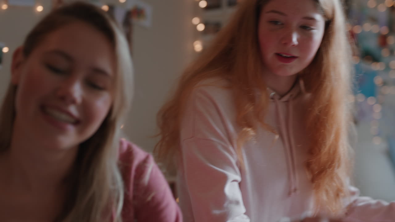 행복한 십대 소녀들이 즉각 사진 카메라를 사용하여 함께 사진을 찍고 가장 친한 친구들이 주말에 집에서 친구 관계를 즐기고 있습니다.