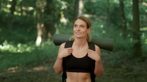 woman carrying a yoga mat in a forest