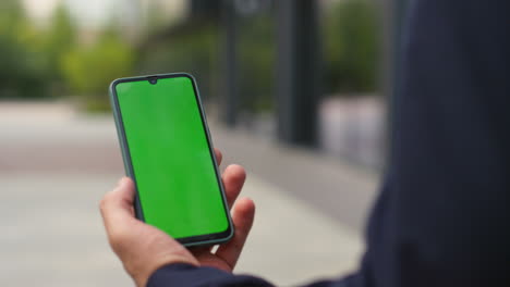 hands holding green smartphone on street closeup. businessman in suit videocall