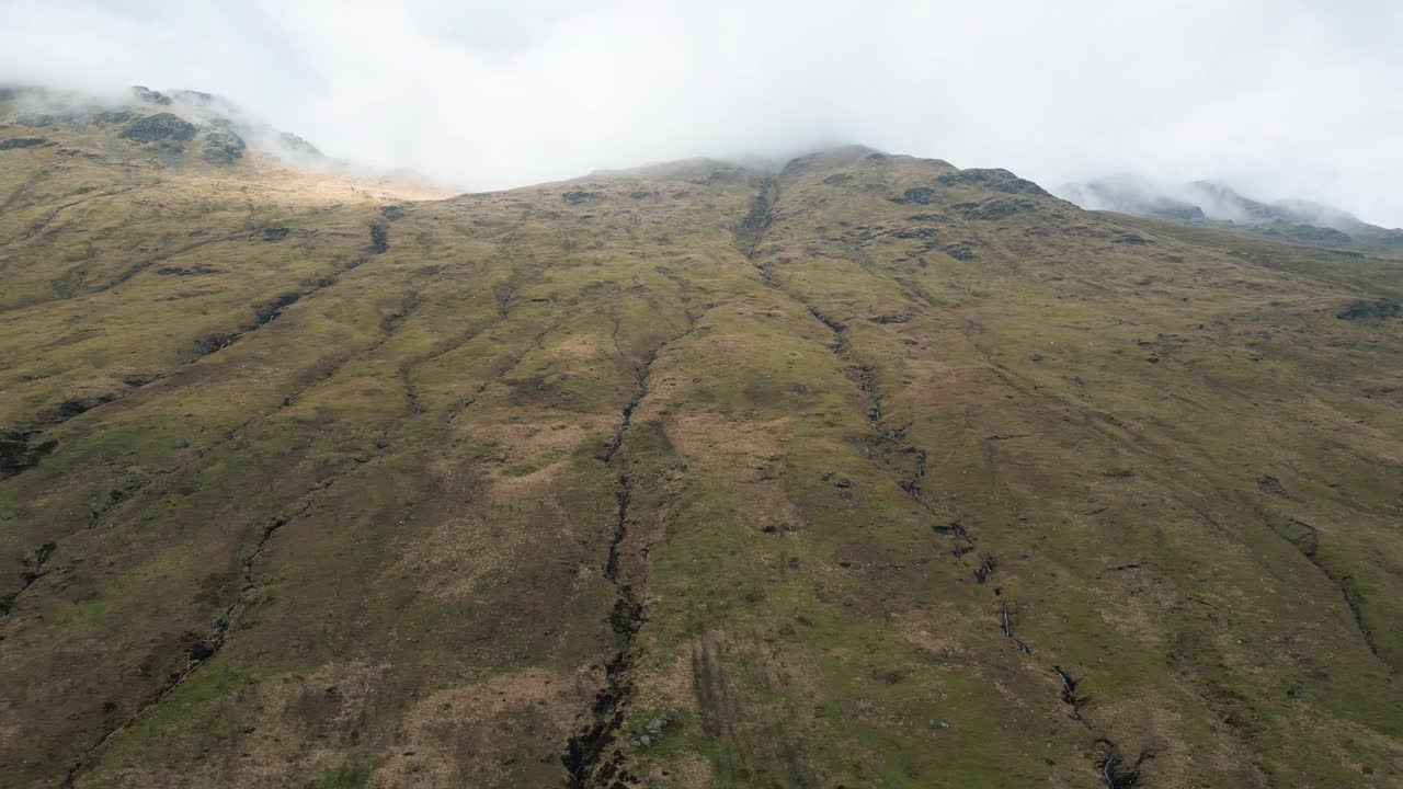 Green Mountainside With Streams of Water and clouds surrounding the Moutain