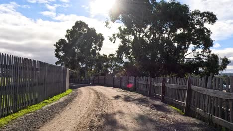 un camino de tierra con cercas de madera y árboles