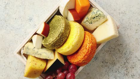 fresh and delicious different kinds of cheeses placed in wooden crate with grapes