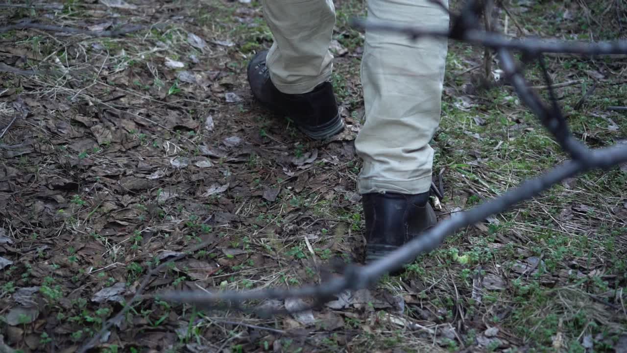 vista cercana de las botas de un hombre caminando en el bosque en cámara lenta