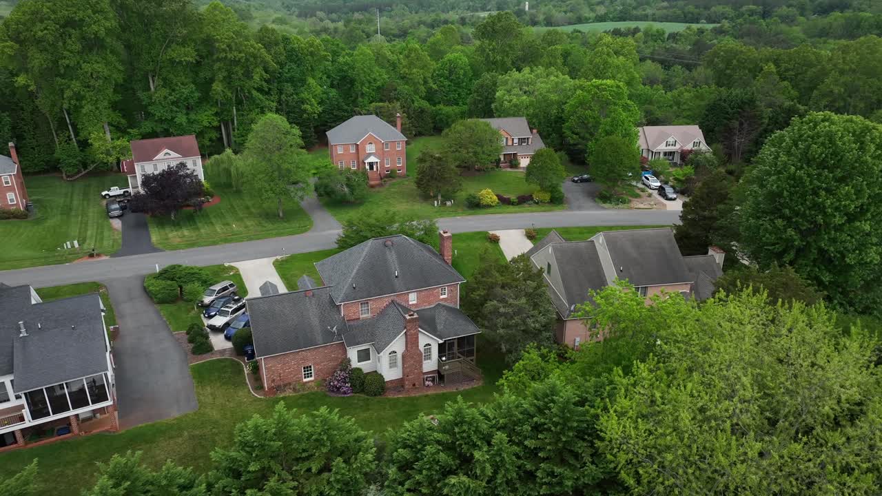 Real estate houses in brick design between green forest trees. Drone approaching. Cloudy day in spring. Parking garages in quiet noble housing area.