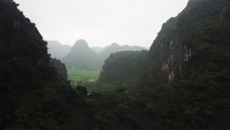 Ascendiendo-Desde-Detrás-De-Dos-Karsts-Para-Revelar-Un-Exuberante-Valle-Verde-Montañoso-De-Tam-Coc