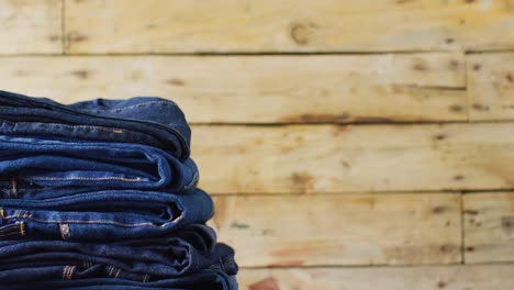 close up of folded jeans with different shades on wooden background with copy space