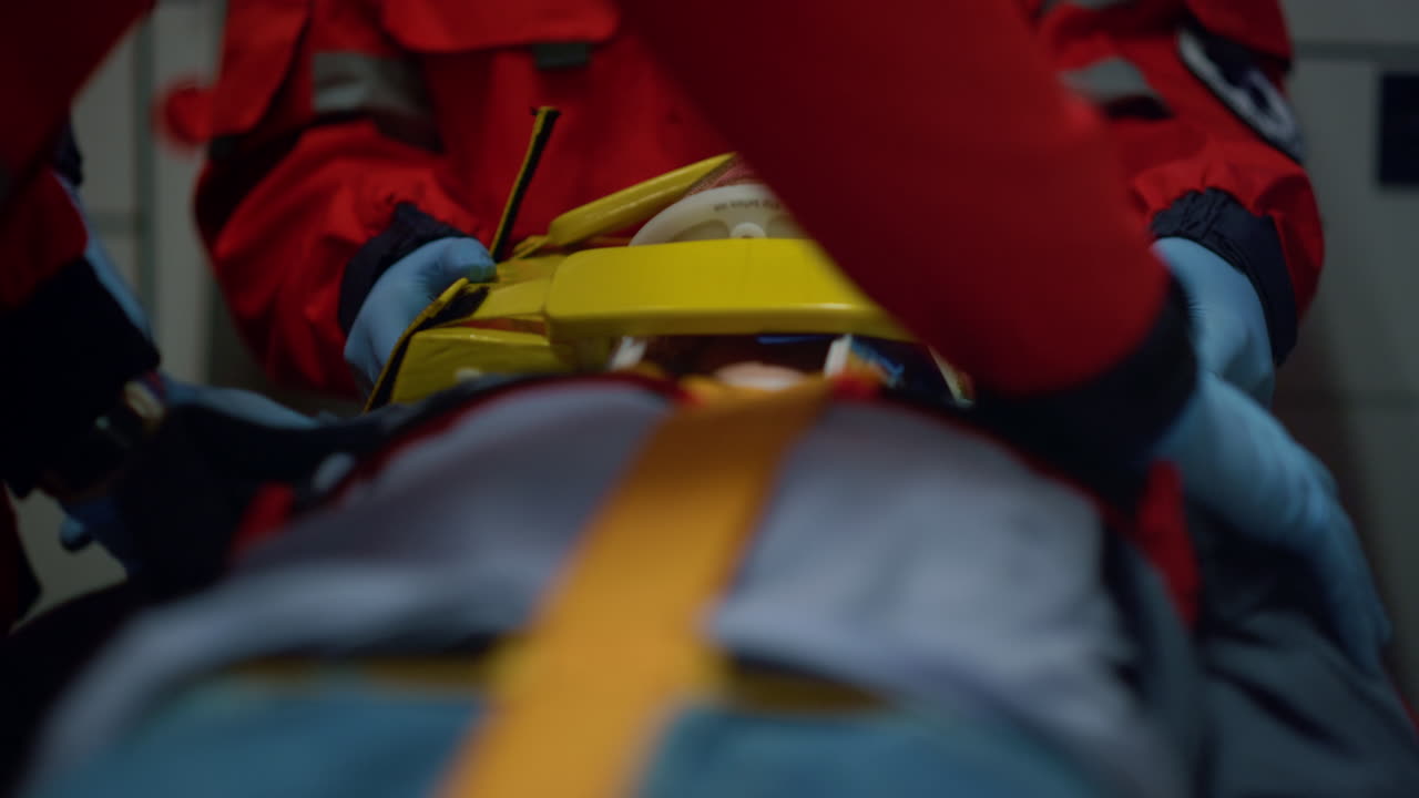 Unrecognizable paramedics rescuing patient on stretchers in emergency vehicle.