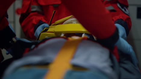 paramédicos irreconocibles rescatando a un paciente en camillas en un vehículo de emergencia.