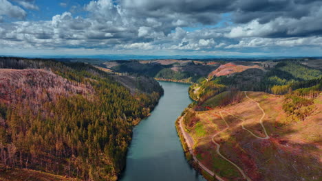 dramatic cloudscape hanging in the sky over the mountainous landscape of oregon. drone flight over the beautiful river flowing among the mountains.