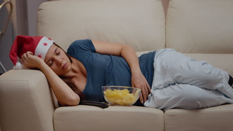 close up of tired woman with santa hat sleeping on sofa