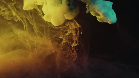 slow motion shot of yellow and blue color paint ink drops in water against black background - inky cloud swirling flowing underwater -abstract smoke explosion animation isolated on black alpha channel