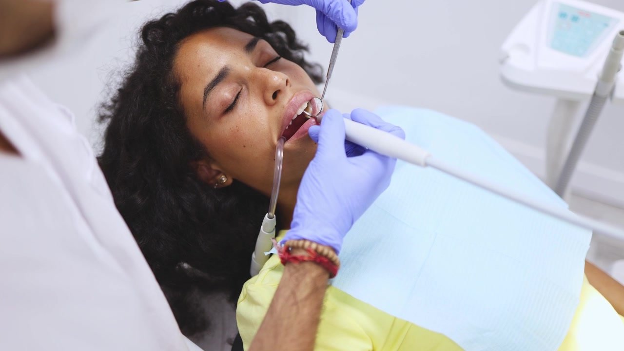 Dentista che esamina i denti di una giovane donna in una clinica dentistica