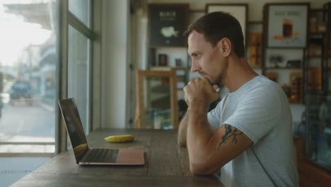 hombre trabajando en una computadora portátil en un café