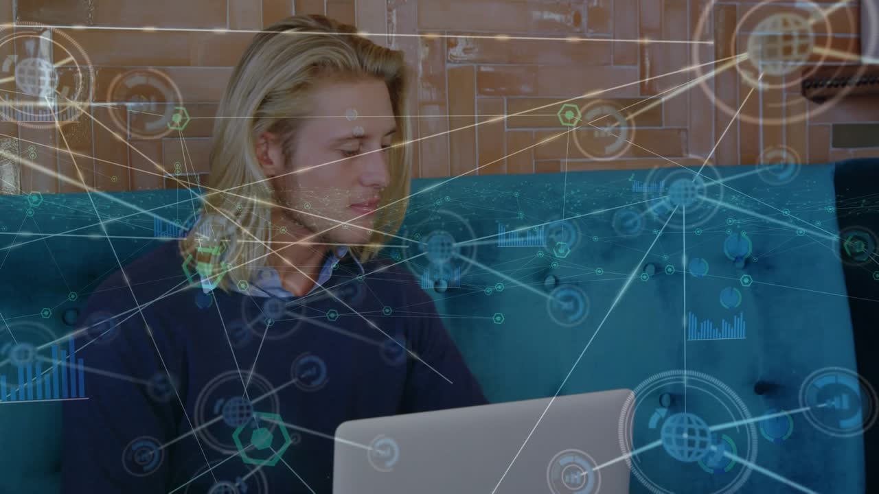 Animation of network of digital icons over caucasian man using laptop and smartphone at office