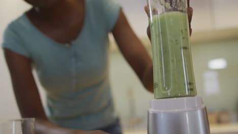 de manos afroamericana mujer atractiva mezclando ingredientes para batido en la cocina