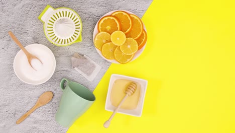 sliced lemons, cup for tea, sugar and honey appear on yellow theme. stop motion