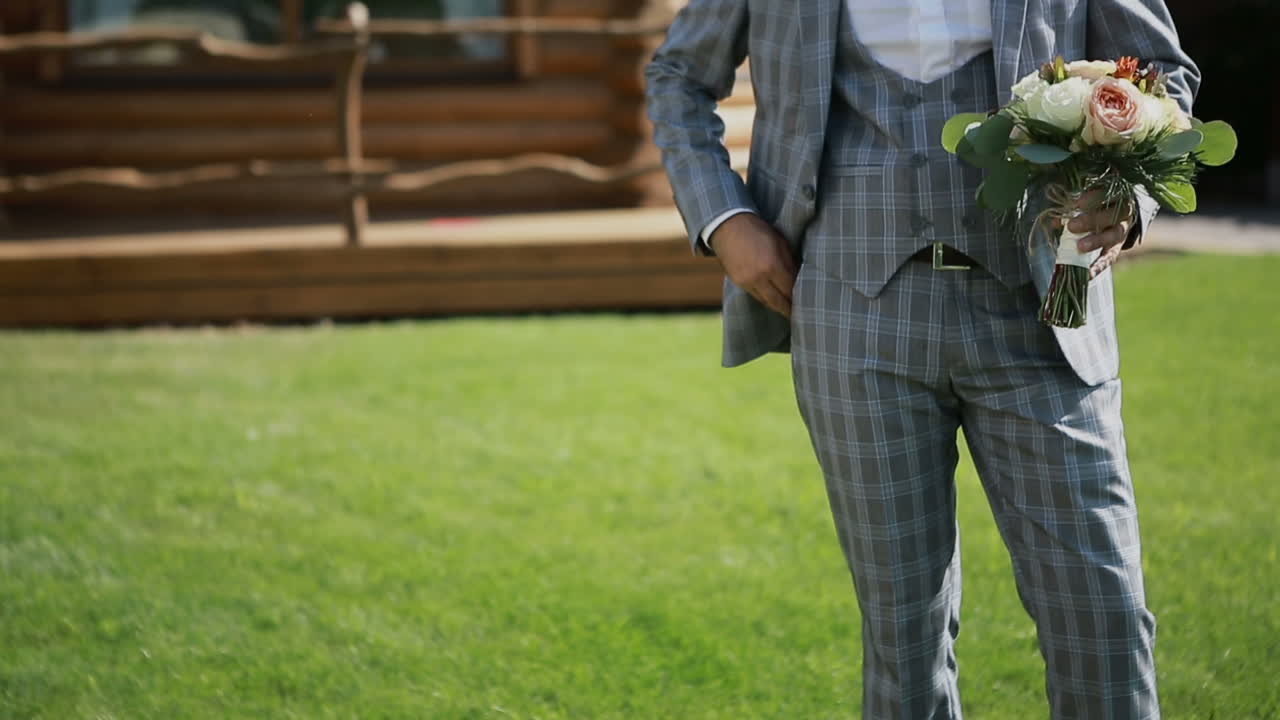 Wedding bouquet with beautiful flowers in the hands of the groom