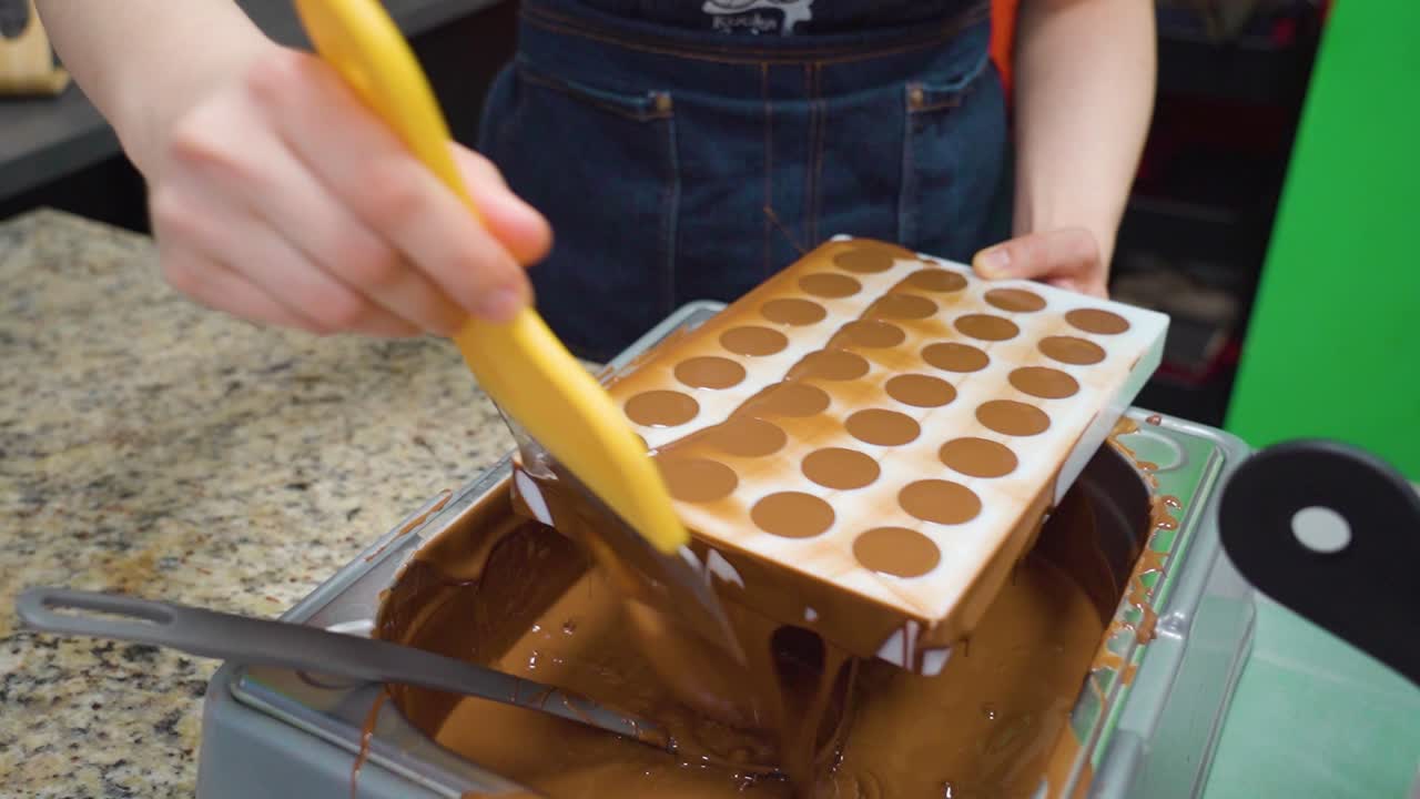 raspando el exceso de chocolate de un molde con una espátula