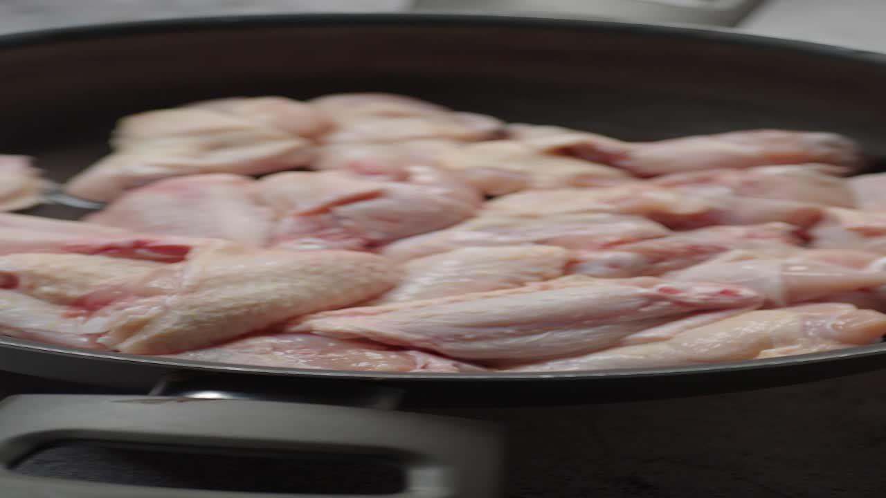 Ali di pollo crude in una padella