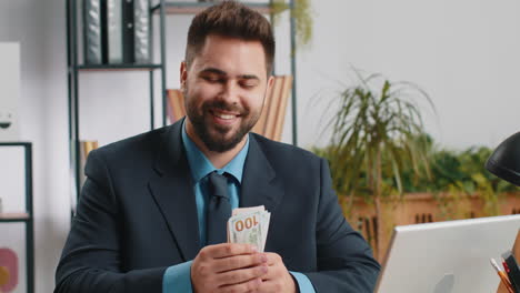 happy businessman holding cash in his office