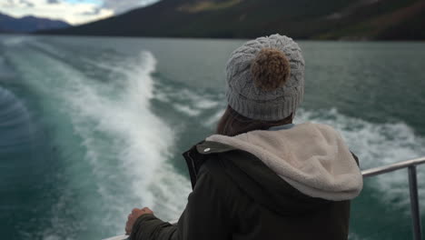 female on back of ferry boat looking at water wakes and scenic coastline of lake maligne, jasper national park, canada, cinematic full frame shot