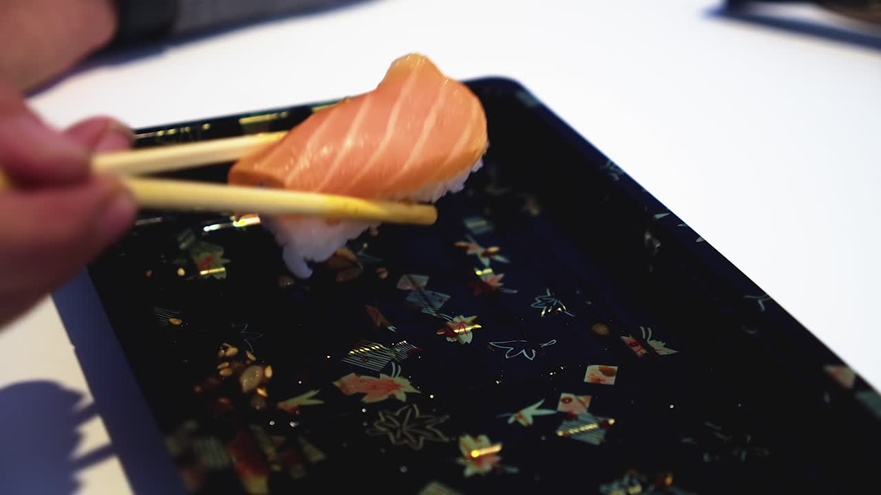 el último pedazo de sake nigiri sushi es arrancado del plato con palillos