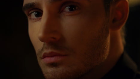 young man face looking ahead indoors. beautiful guy posing in black background.