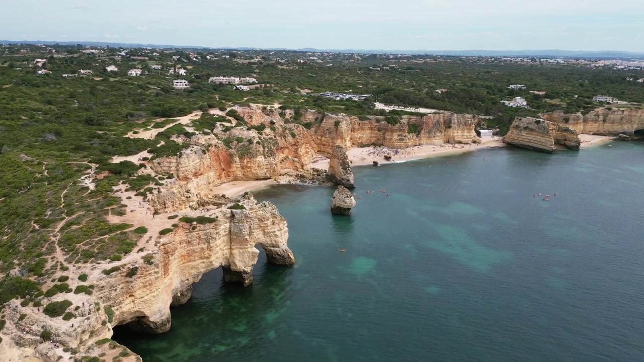 Luftaufnahmen mit Drohne von der Küste Benagils, Portugal: goldene Klippen, türkisfarbenes Atlantikwasser und dramatische Küstenfelsenformationen unter sonnigem Licht. Ideal für Reiseprojekte.