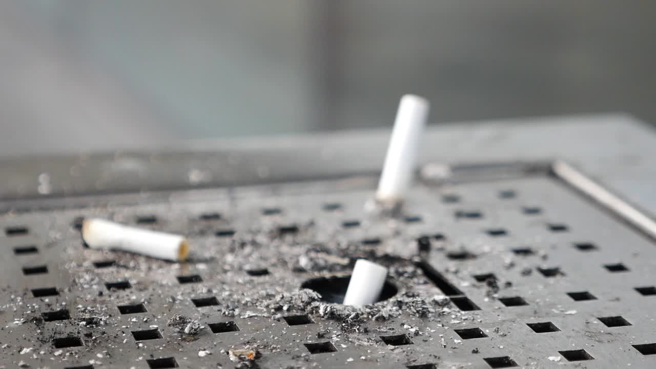primer plano de las colillas de cigarrillos en un cenicero público